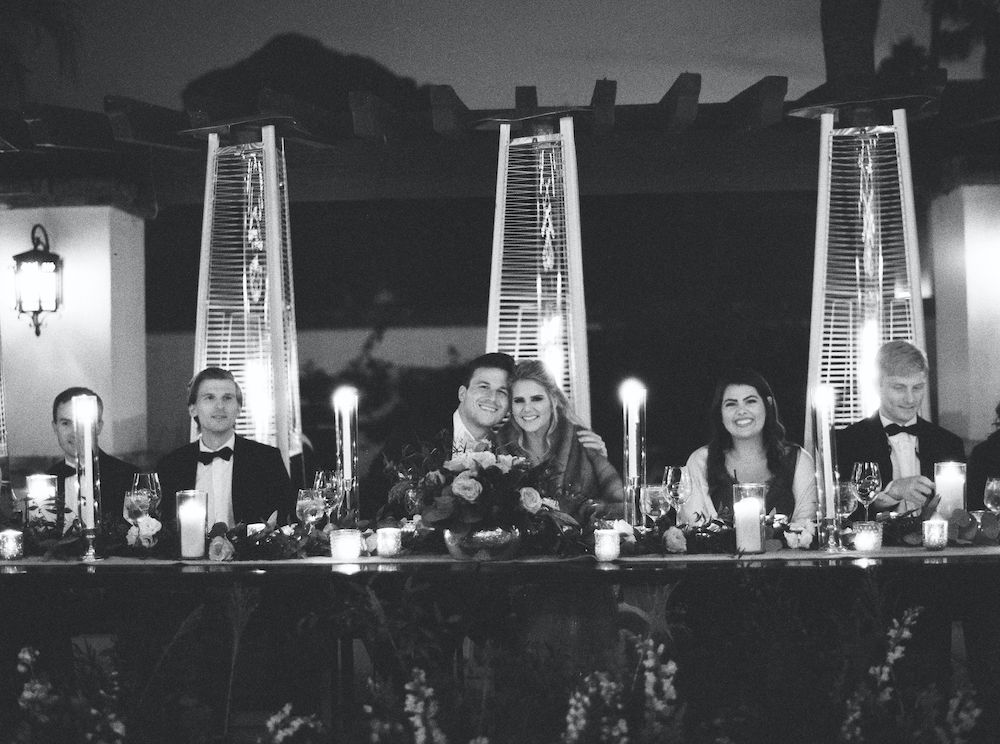 black and white photo of bride and groom smiling at head table during outdoor reception at Omni Montelucia.